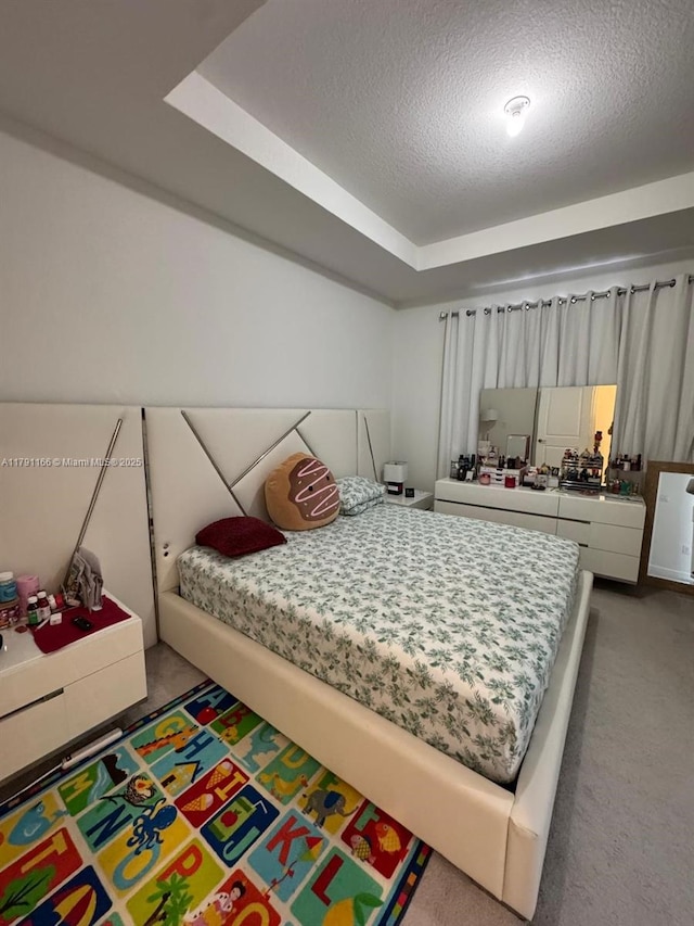 bedroom with a textured ceiling, a raised ceiling, and carpet