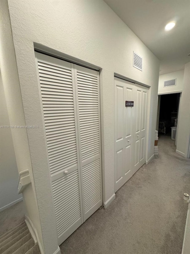 hall featuring baseboards, visible vents, and carpet flooring