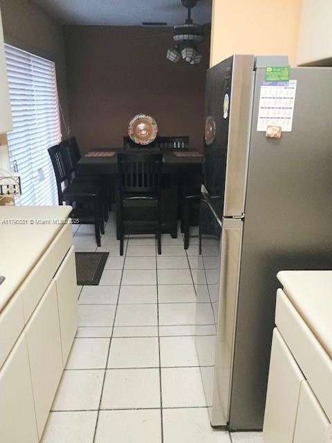 interior space with white cabinets, light tile patterned floors, light countertops, and freestanding refrigerator
