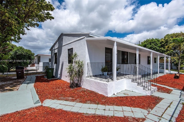 1710 E 6th Ave, Hialeah, FL 33010 - view of property exterior with covered porch, stucco siding, and fence