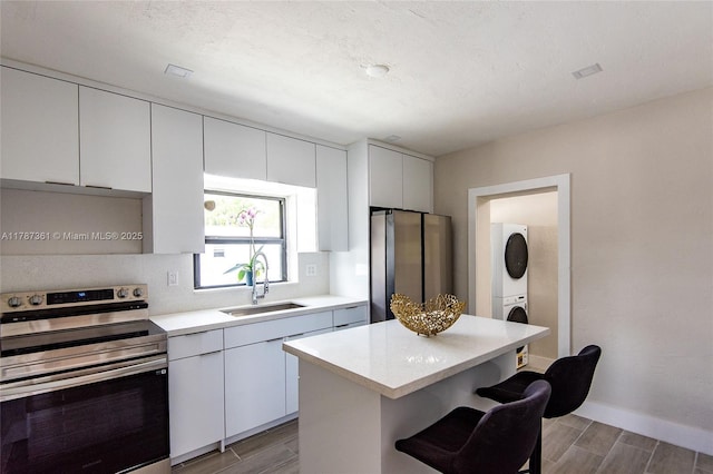 1710 E 6th Ave, Hialeah, FL 33010 - kitchen with stainless steel appliances, stacked washing machine and dryer, a sink, a kitchen breakfast bar, and wood finish floors