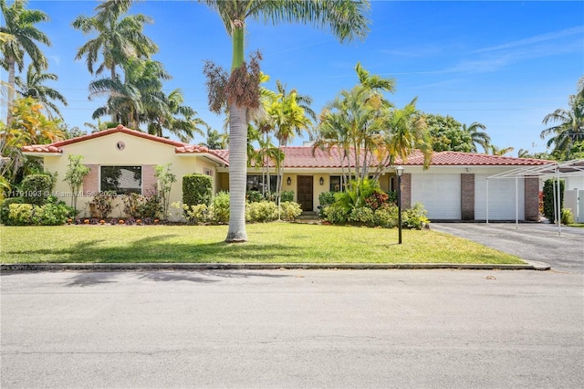 view of front of property with driveway, a front yard, a tile roof, and a garage