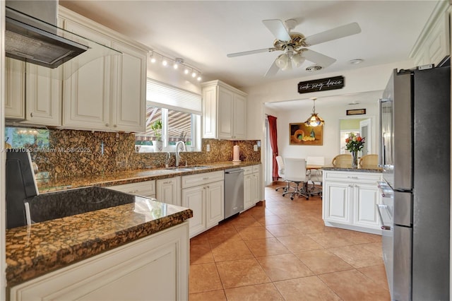 kitchen with a sink, stainless steel appliances, light tile patterned floors, tasteful backsplash, and a ceiling fan