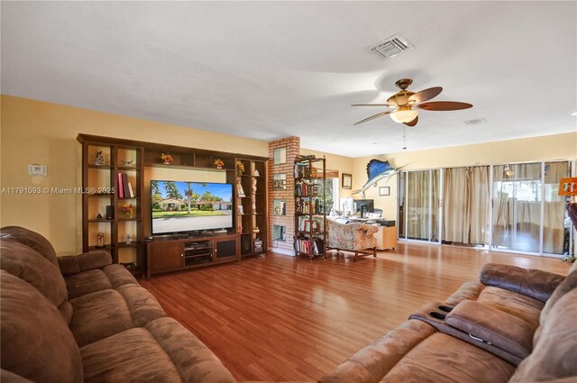 living area with a wealth of natural light, visible vents, wood finished floors, and a ceiling fan