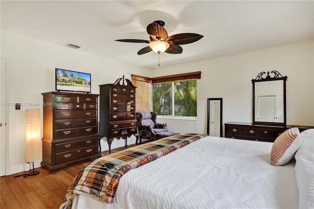 bedroom featuring a ceiling fan, visible vents, and wood finished floors