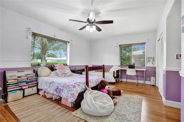 bedroom with baseboards, wood finished floors, a ceiling fan, and multiple windows
