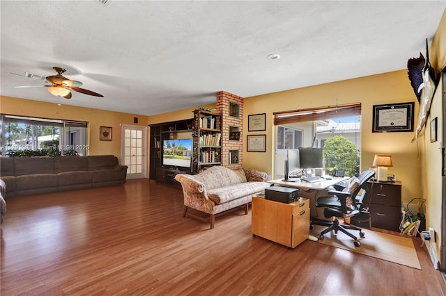 living room with a textured ceiling, wood finished floors, and a ceiling fan