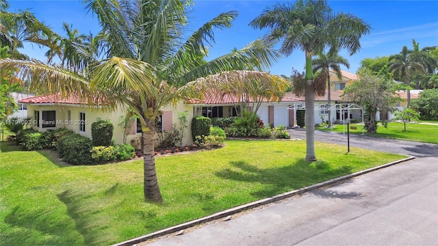 view of front of property with driveway, stucco siding, a front lawn, and a tile roof