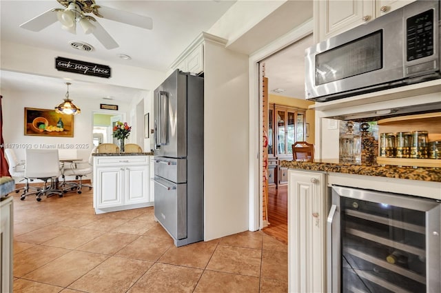 kitchen featuring stainless steel appliances, wine cooler, light tile patterned flooring, dark stone countertops, and white cabinets
