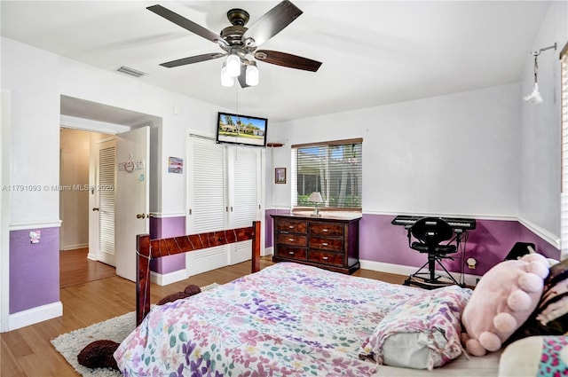 bedroom featuring wood finished floors, a closet, ceiling fan, baseboards, and visible vents