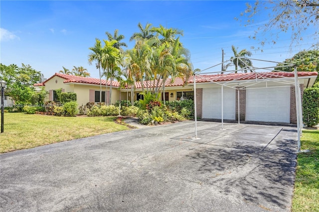single story home featuring a front lawn, stucco siding, driveway, a tiled roof, and an attached garage