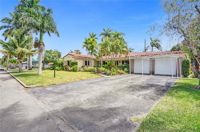 ranch-style home featuring a front yard, a garage, a tiled roof, and aphalt driveway