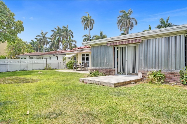 back of property with a patio, a yard, board and batten siding, and fence
