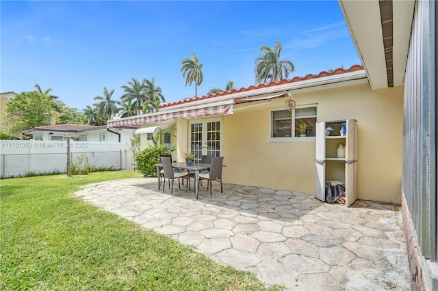 back of house with stucco siding, fence, a patio, french doors, and a lawn