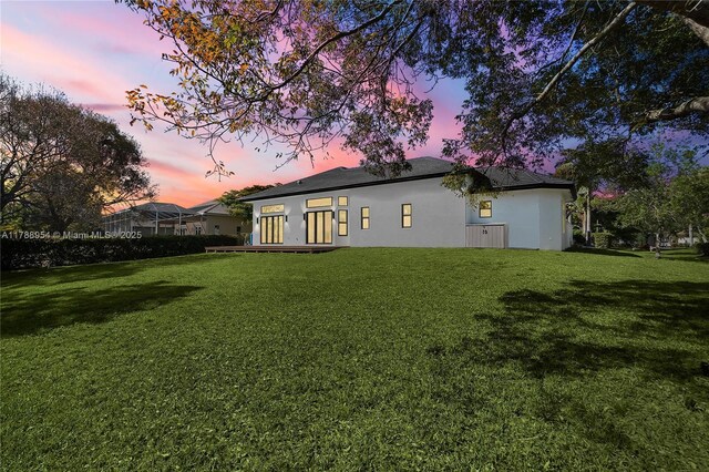 499 SW Squire Johns Ln, Palm City, FL 34990 - back of property at dusk with a lawn and stucco siding