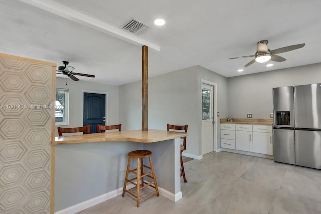 kitchen featuring stainless steel fridge with ice dispenser, a ceiling fan, butcher block counters, and visible vents