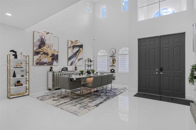 entryway featuring recessed lighting, baseboards, and a towering ceiling