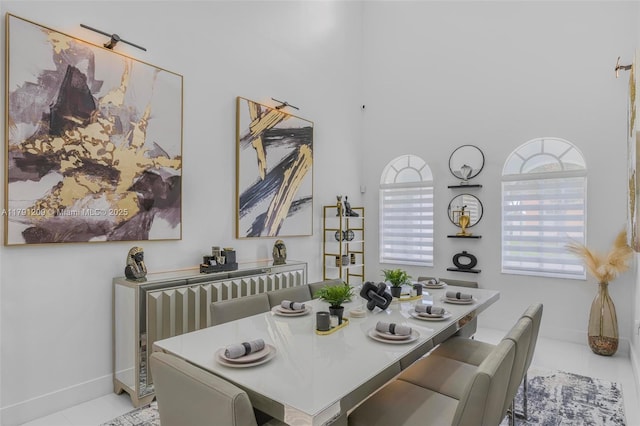 dining space with baseboards and a towering ceiling