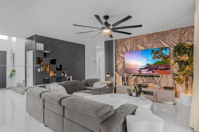 living area with a ceiling fan, a textured ceiling, and an accent wall