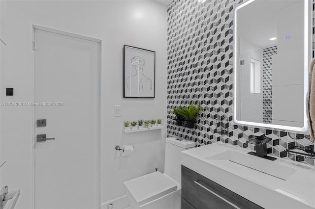 bathroom featuring vanity, toilet, and tasteful backsplash