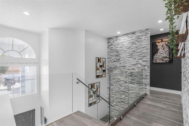 staircase featuring recessed lighting, a textured ceiling, and wood finished floors