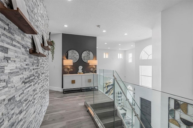 staircase with recessed lighting, a textured ceiling, and wood finished floors