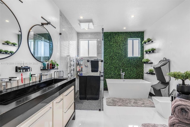 bathroom with vanity, a textured ceiling, tile patterned floors, a soaking tub, and a stall shower