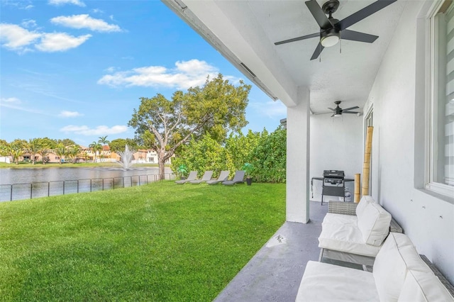 view of yard with a ceiling fan, a water view, and an outdoor living space
