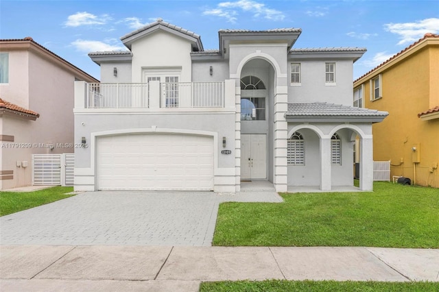 mediterranean / spanish-style house featuring a tiled roof, a front yard, decorative driveway, a balcony, and stucco siding