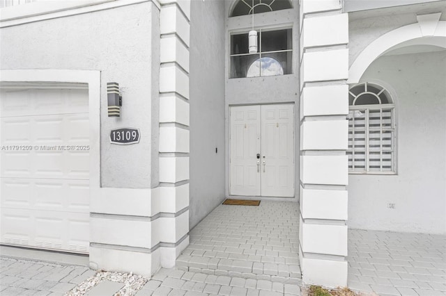 doorway to property featuring a garage and stucco siding