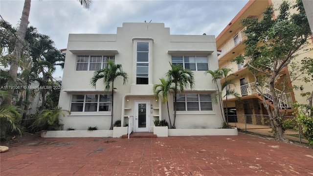 art deco home featuring stucco siding and fence