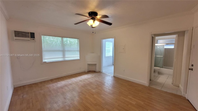 unfurnished bedroom with baseboards, a wall unit AC, crown molding, and light wood-style flooring