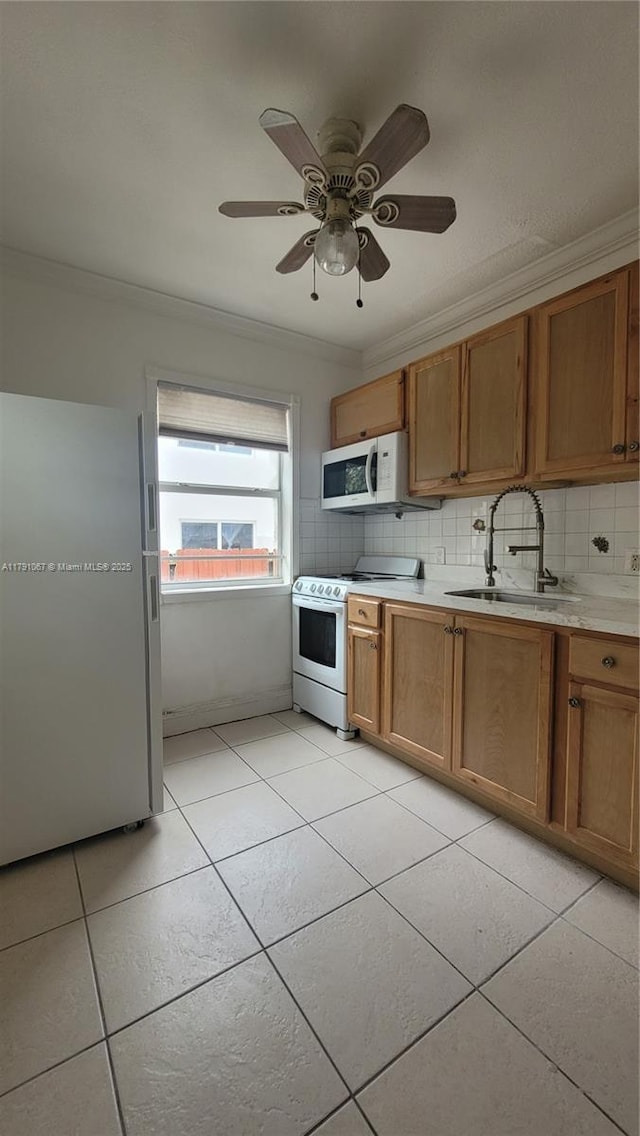 kitchen with ornamental molding, white appliances, backsplash, and a sink