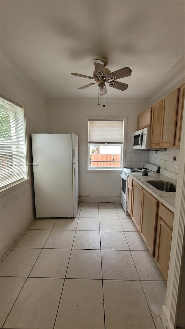 kitchen with a sink, light tile patterned floors, white appliances, tasteful backsplash, and light countertops