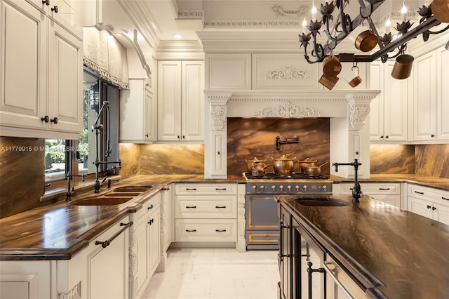 kitchen with double oven range, white cabinetry, tasteful backsplash, crown molding, and a sink