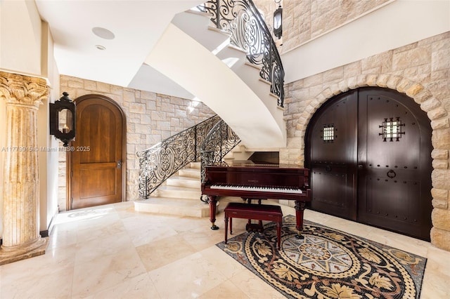 entryway featuring decorative columns, stairway, and arched walkways