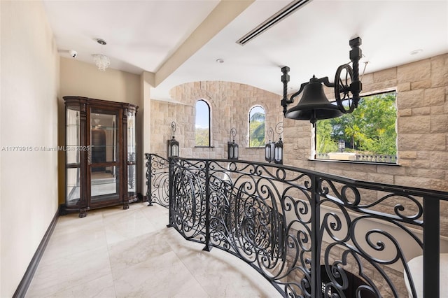 hallway featuring a notable chandelier, visible vents, and baseboards