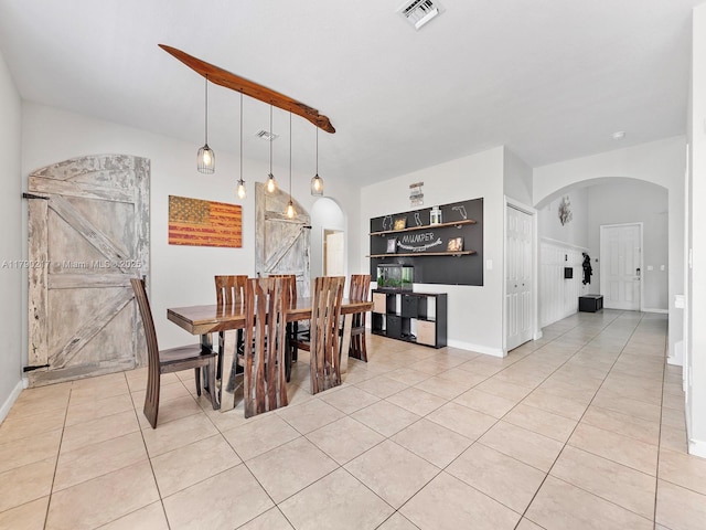 dining room featuring light tile patterned floors, arched walkways, baseboards, and visible vents