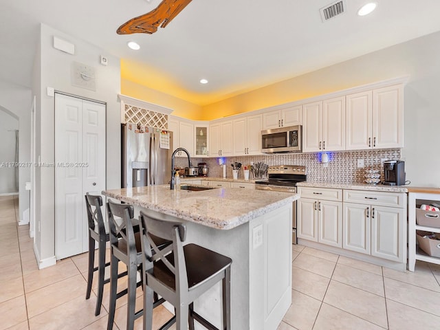 kitchen featuring visible vents, decorative backsplash, light tile patterned flooring, a sink, and appliances with stainless steel finishes