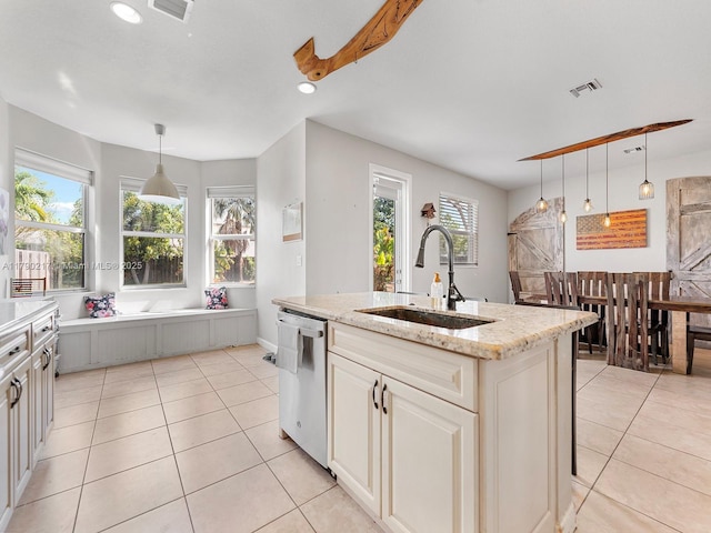 kitchen featuring visible vents, dishwasher, a center island with sink, a sink, and light tile patterned floors