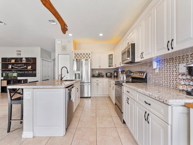 kitchen featuring visible vents, tasteful backsplash, a sink, light tile patterned floors, and stainless steel appliances