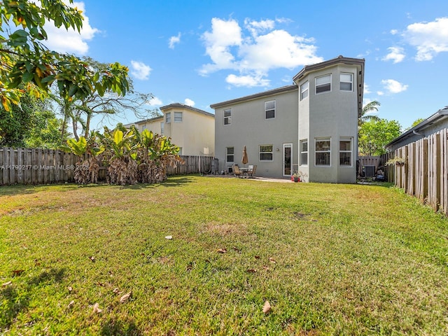 back of house with a fenced backyard, stucco siding, and a yard