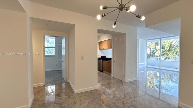spare room featuring marble finish floor, an inviting chandelier, a wealth of natural light, and baseboards