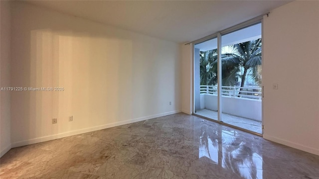spare room featuring floor to ceiling windows and baseboards