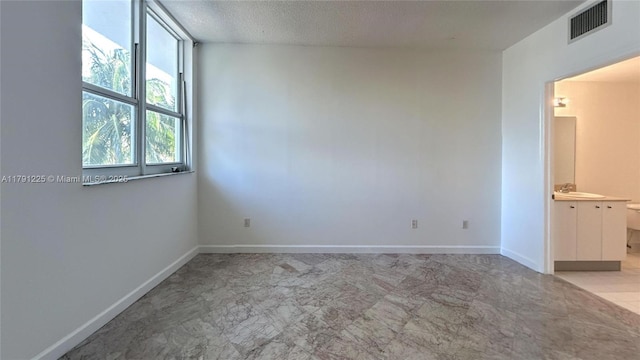 empty room featuring baseboards, visible vents, a textured ceiling, and a sink
