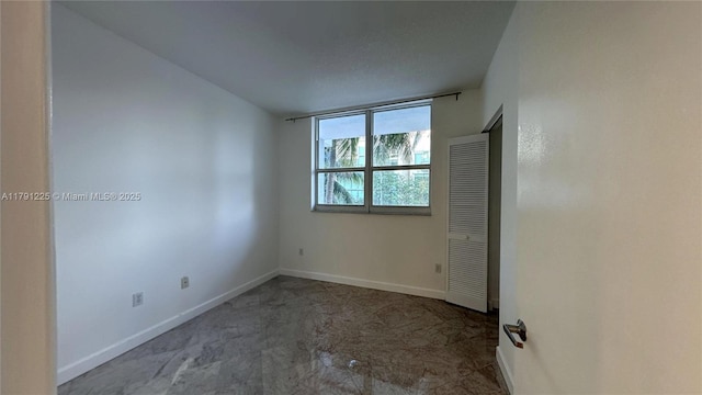 unfurnished room with baseboards