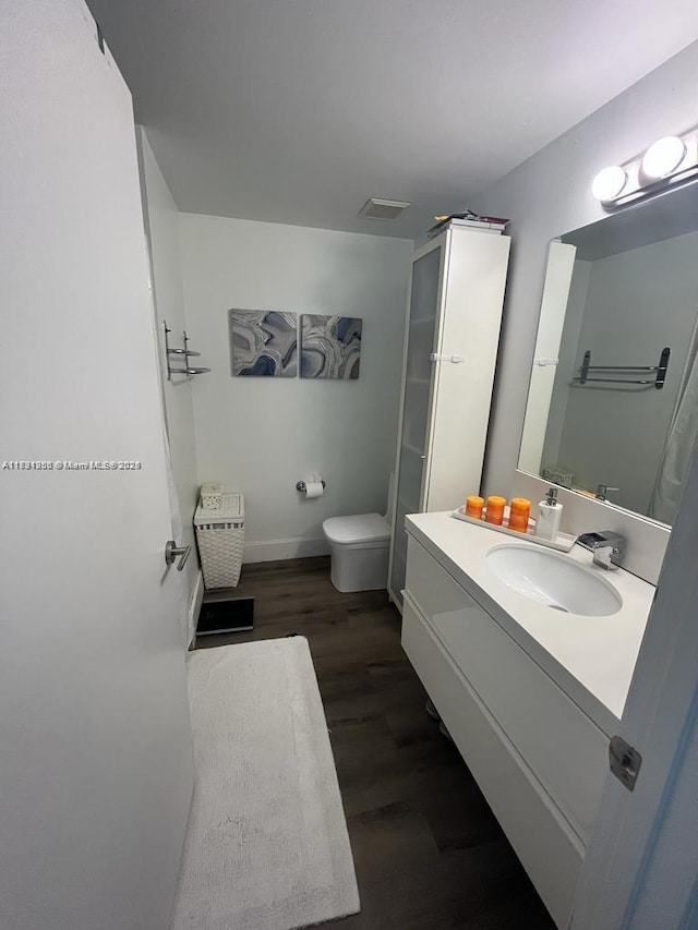bathroom with visible vents, baseboards, toilet, wood finished floors, and vanity