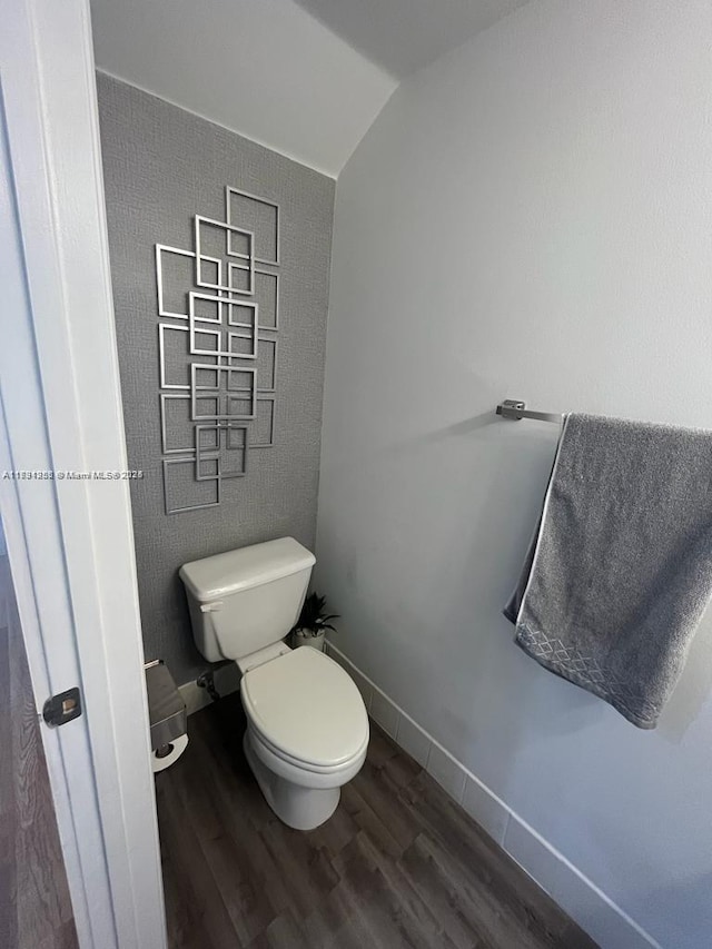 bathroom with wood finished floors, toilet, and lofted ceiling
