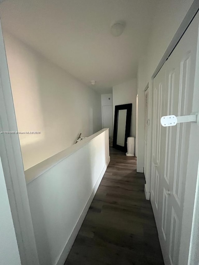 hallway with an upstairs landing, dark wood-style flooring, and baseboards