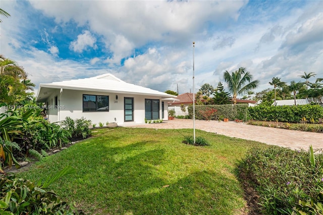 exterior space featuring a lawn, decorative driveway, stucco siding, and fence